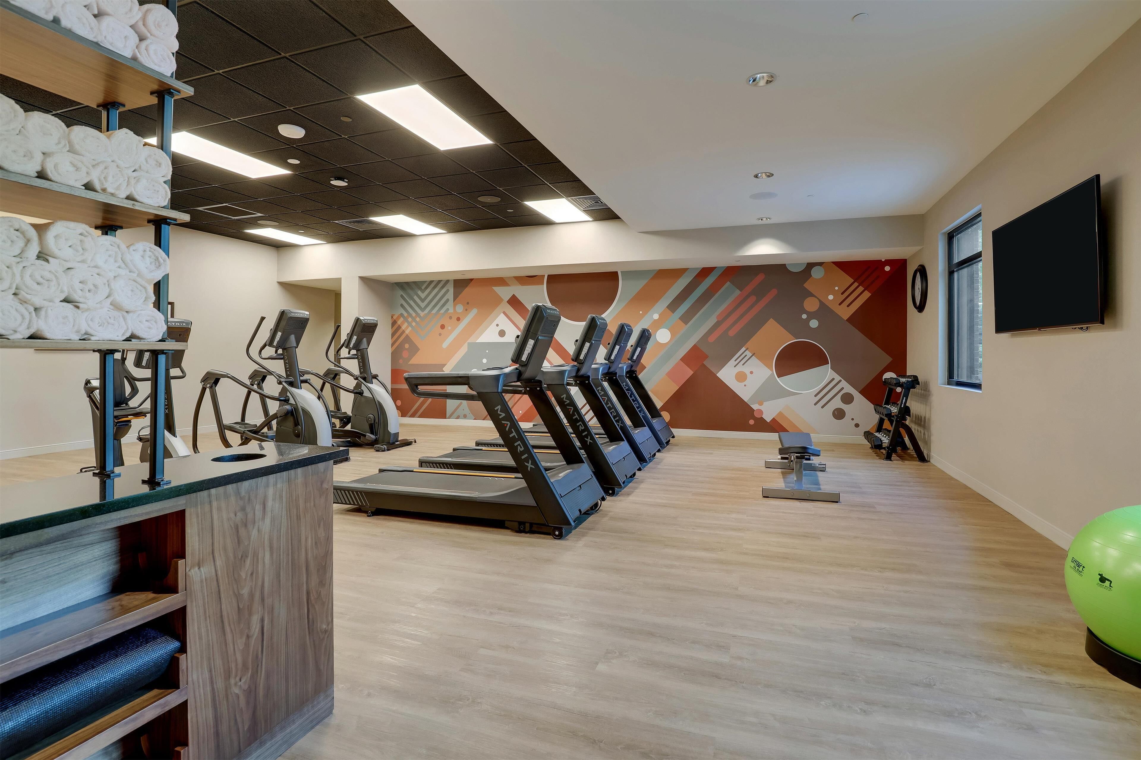 A gym with treadmills, exercise bikes, and a yoga ball.