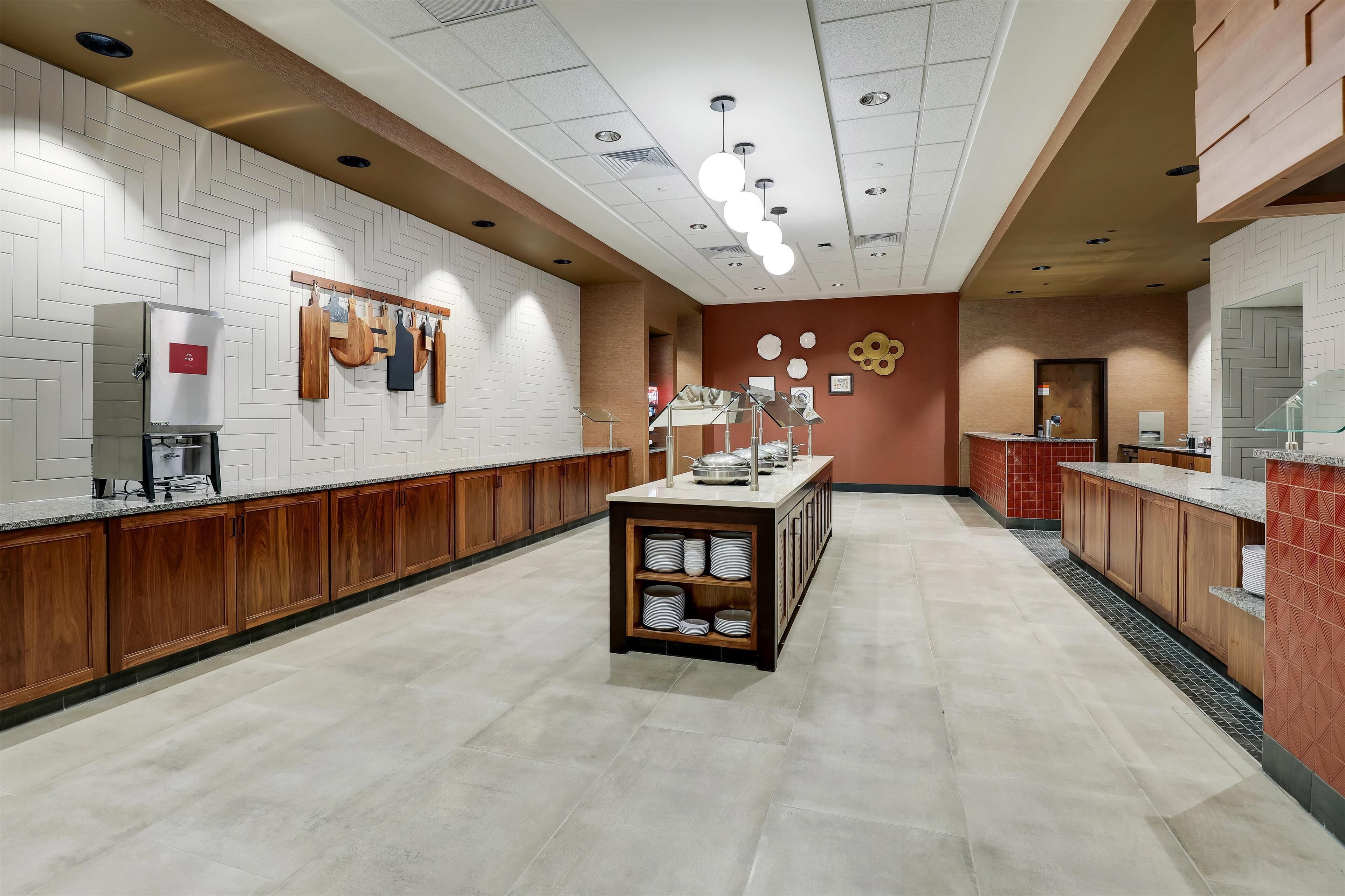 Une cuisine moderne avec des carreaux blancs disposés en motif chevron, des armoires en bois et un îlot central doté de rangements.