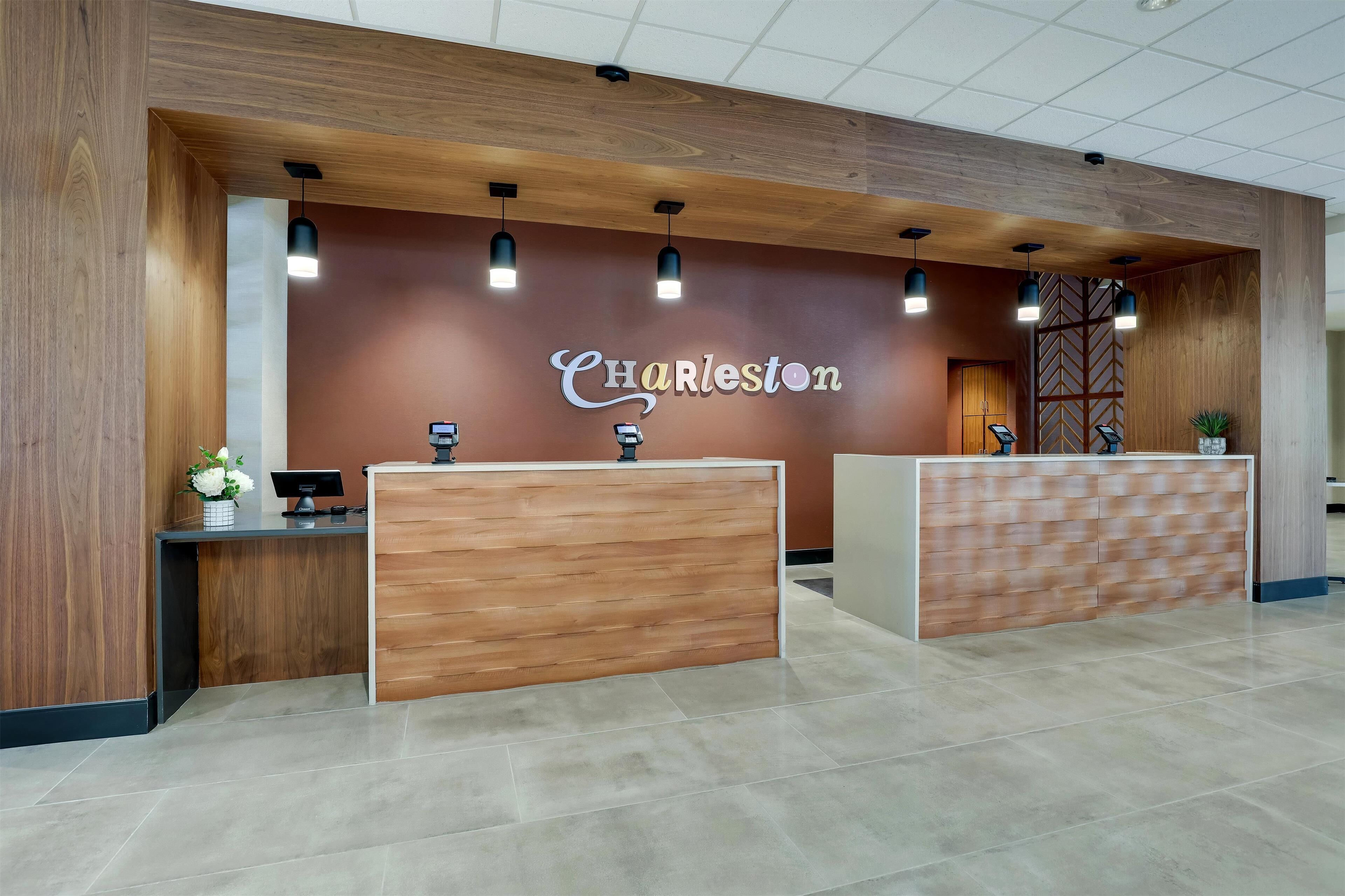 A reception area with a wooden reception desk, a wall-mounted sign reading "Charleston," and pendant lighting.