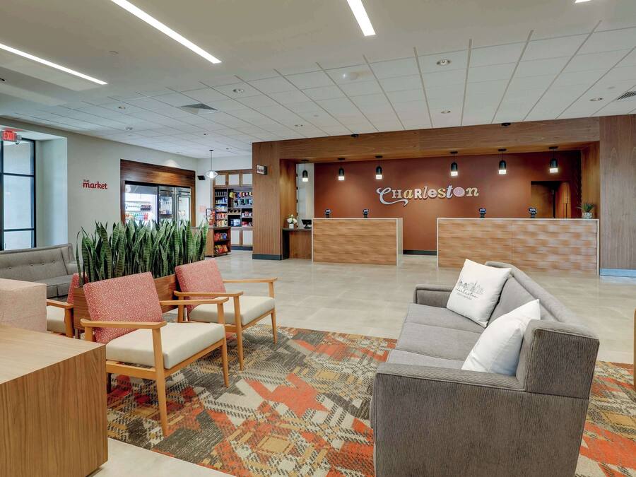 A modern lobby with a reception desk, seating area, and a coffee machine.