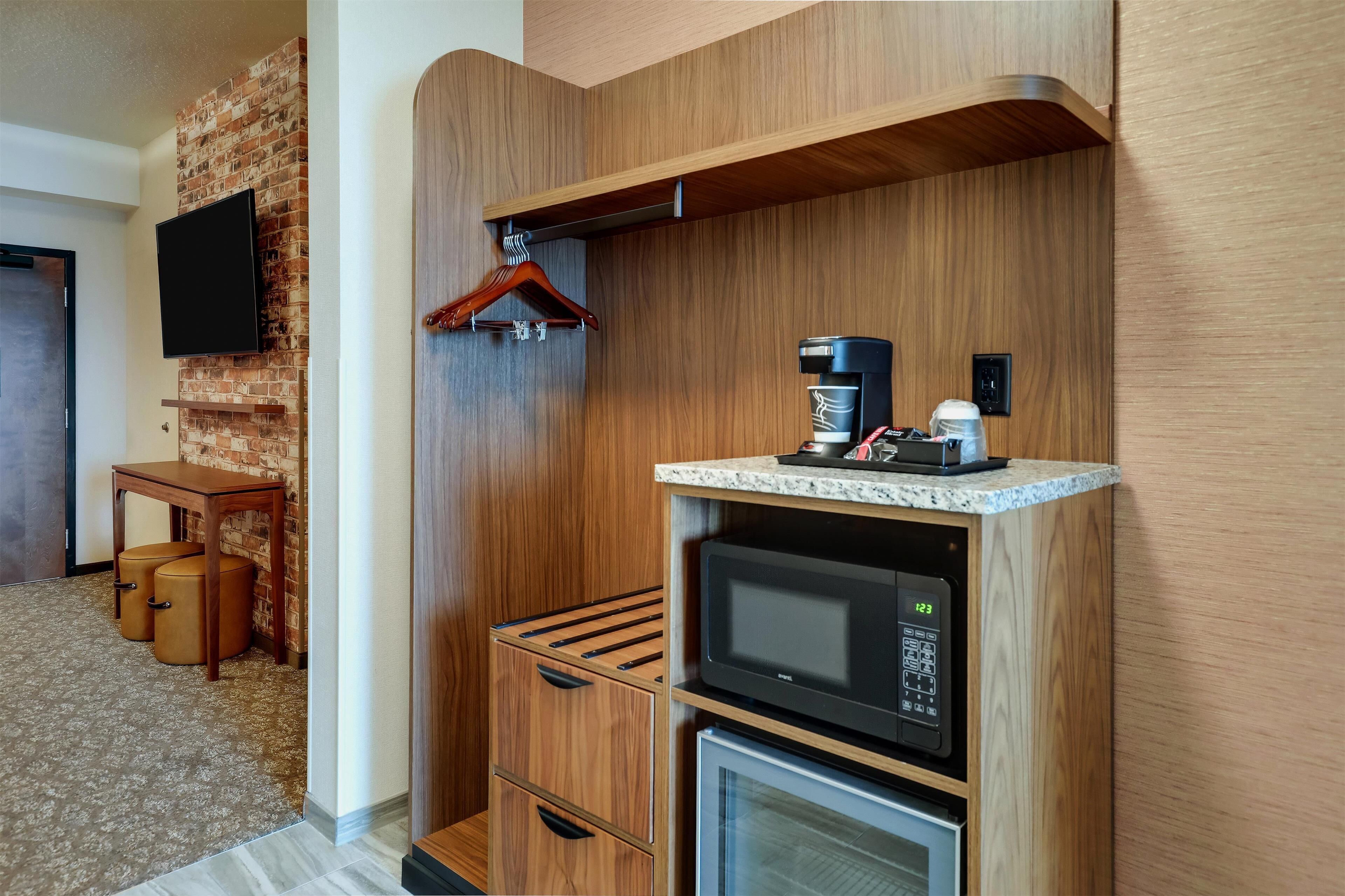 Une petite cuisine équipée d’un four à micro-ondes, d’une machine à café et d’un porte-manteau mural.