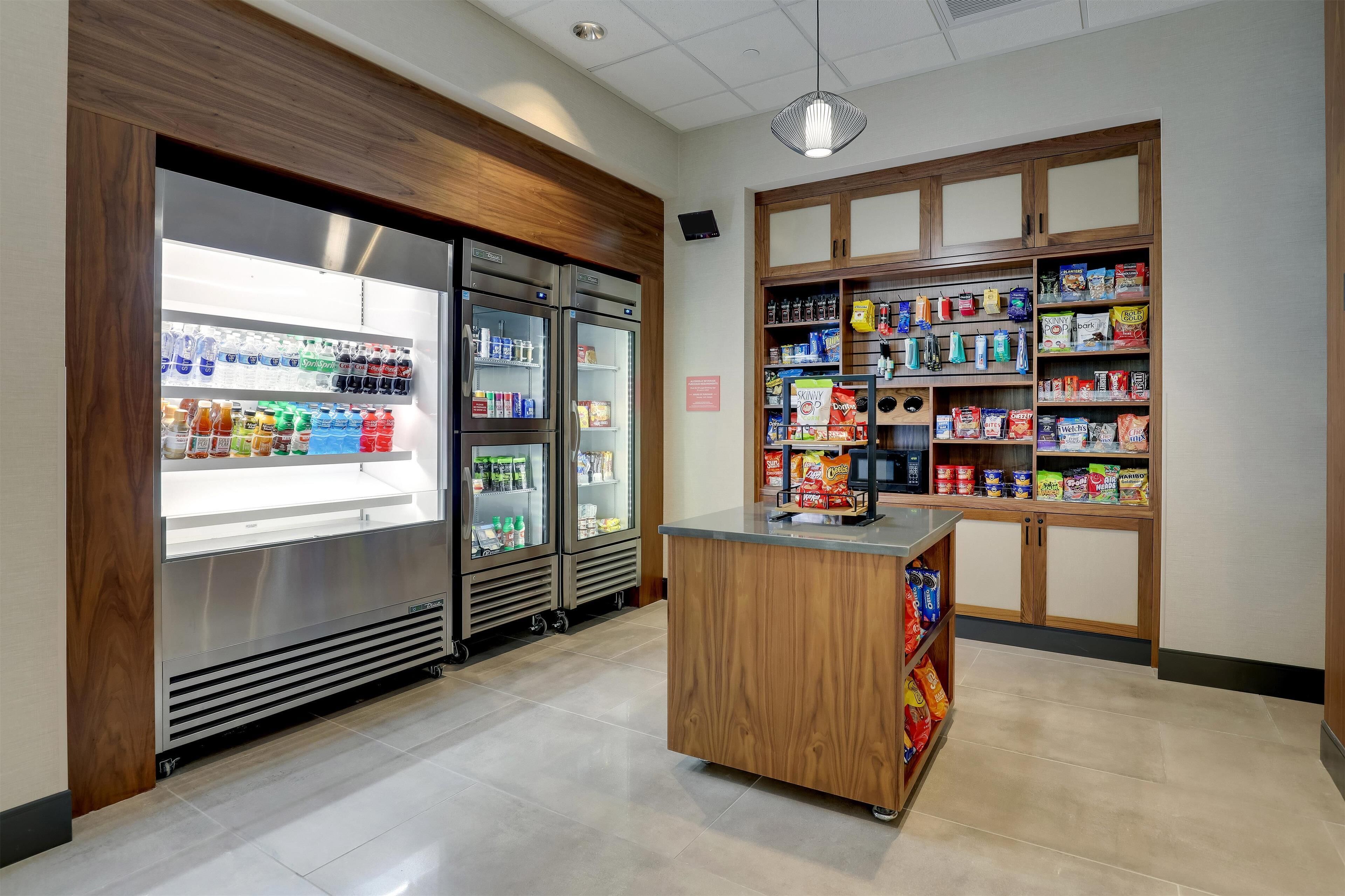 A clean, modern kitchenette with a refrigerator, a microwave, and a wooden island with a sink.