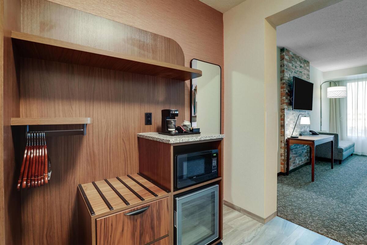 Une chambre d’hôtel compacte comprenant un coin cuisine, un téléviseur à écran plat, une petite table et un canapé.
