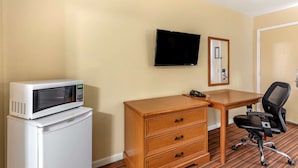 A hotel room with a microwave on a mini-fridge, a wooden dresser, a desk, a black office chair, and a flat-screen TV mounted on the wall. - Econo Lodge Erlanger - Cincinnati Airport (Erlanger)
