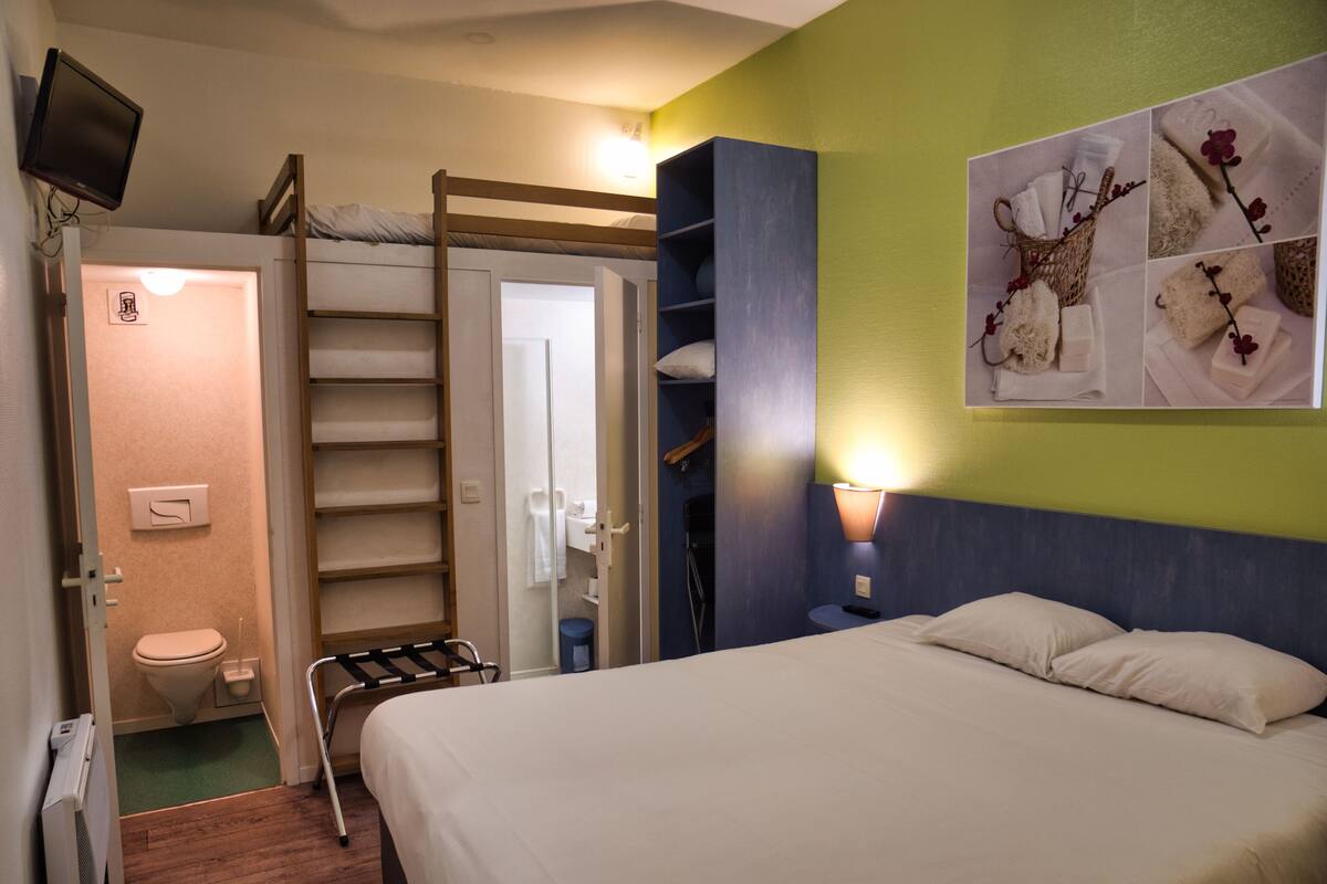 A hotel room with a bed, a bathroom, and a TV.