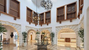 A spacious lobby with a central round table, multiple wooden-framed windows, and a reception area. - Pine Cliffs Hotel, a Luxury Collection Resort, Algarve (Albufeira)