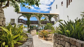 A courtyard with stone walls, a cobblestone path, and arches.
