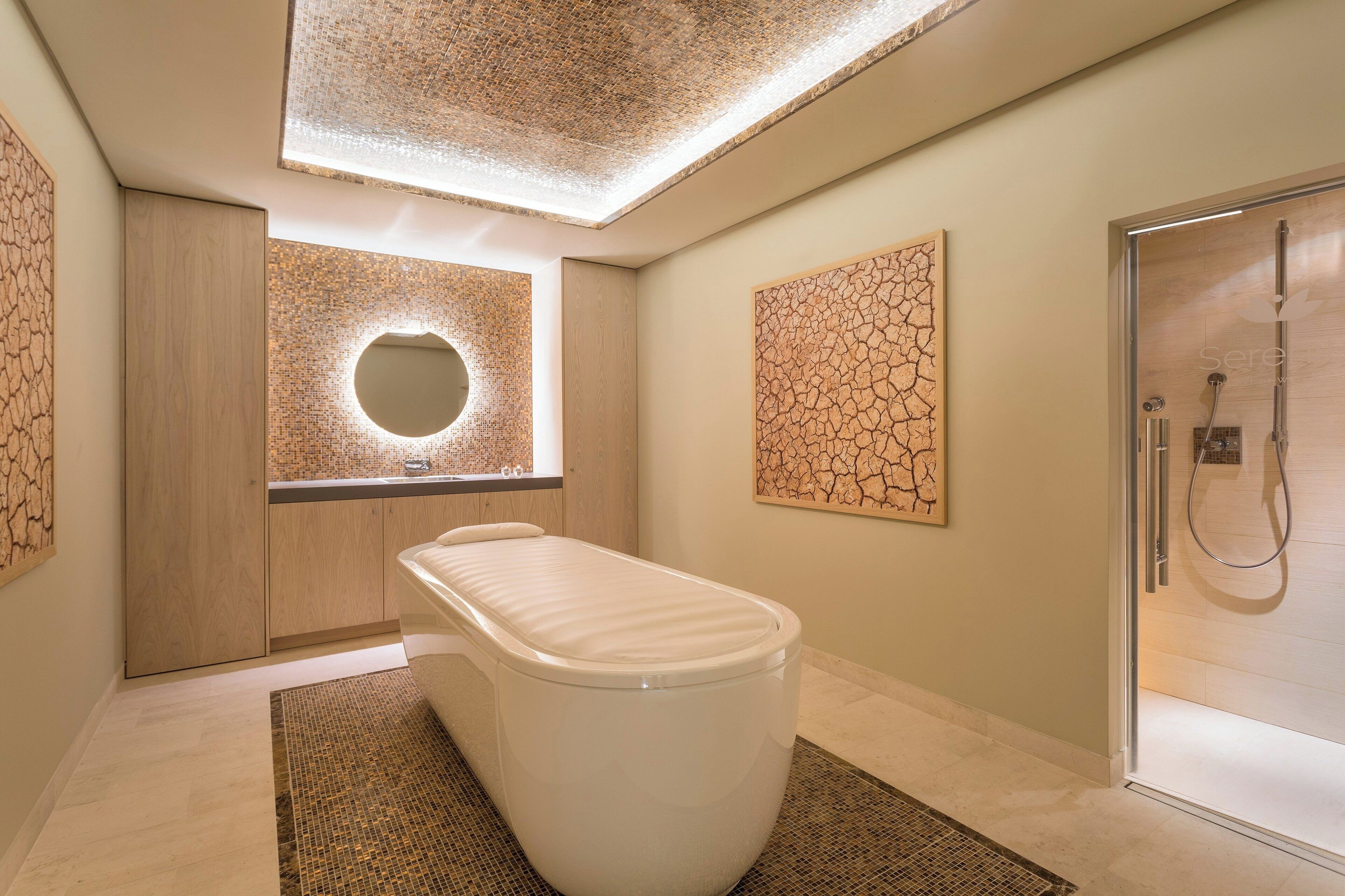 A modern bathroom with a freestanding bathtub, a glass-enclosed shower, and a skylight ceiling.