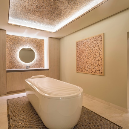 A modern bathroom with a freestanding bathtub, a glass-enclosed shower, and a skylight ceiling.