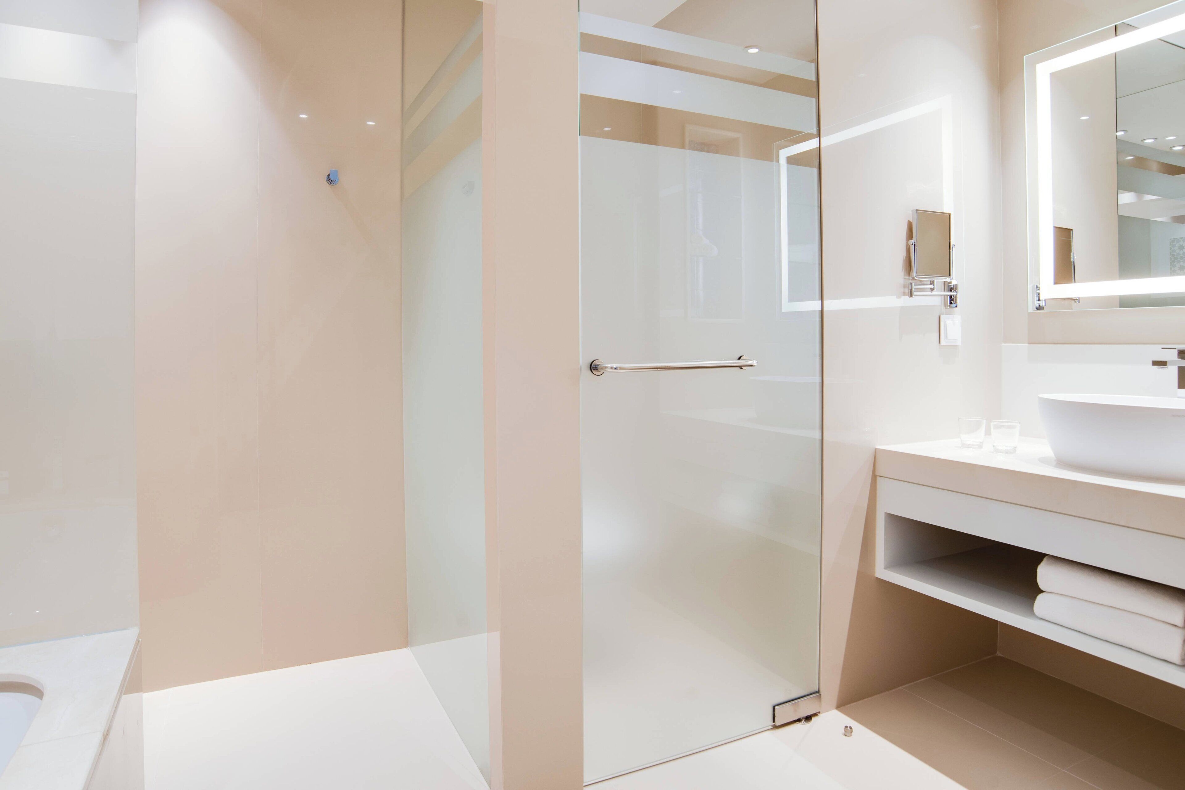 Un baño moderno con cabina de ducha de vidrio, un tocador blanco con espejo y un inodoro.