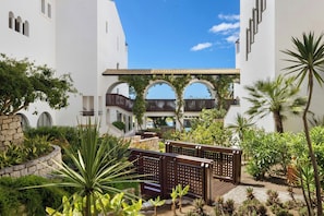 A courtyard with white buildings, arched walkways, and lush greenery.