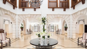 A spacious lobby with a central round table, flanked by seating areas, and a high ceiling with wooden beams and windows. - Pine Cliffs Hotel, a Luxury Collection Resort, Algarve (Albufeira)