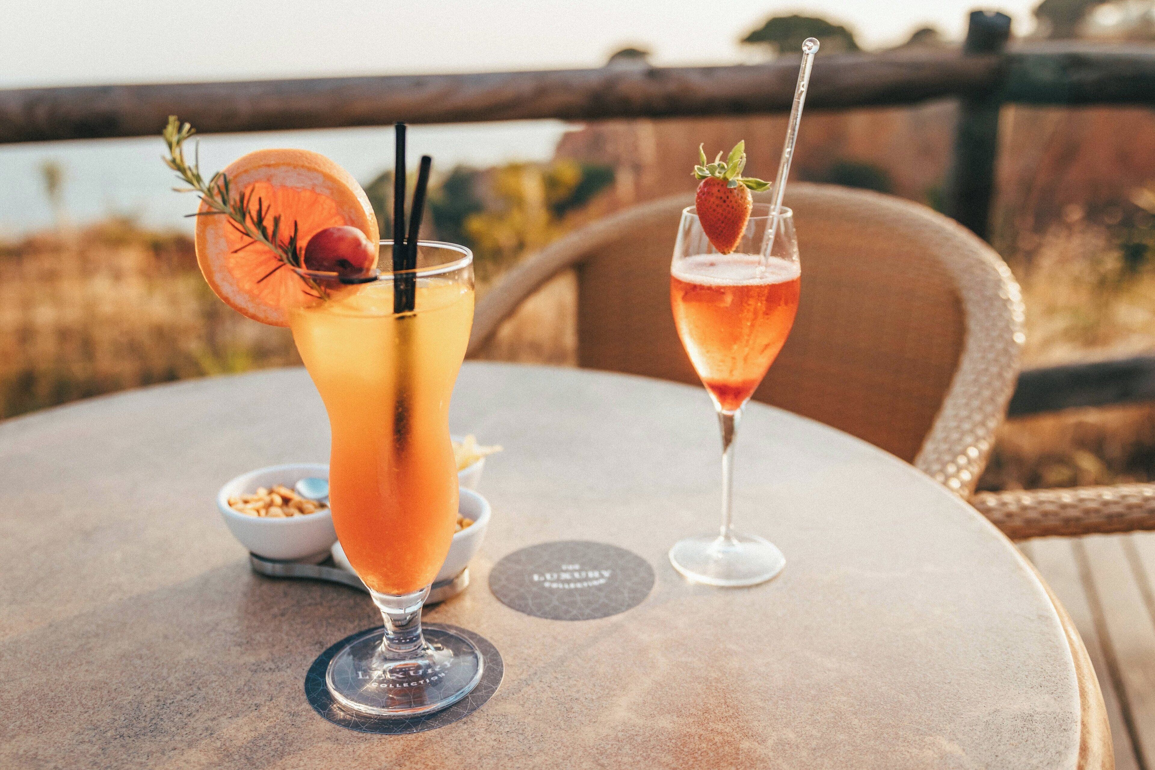 Two cocktails on a round table with a view of the outdoors.