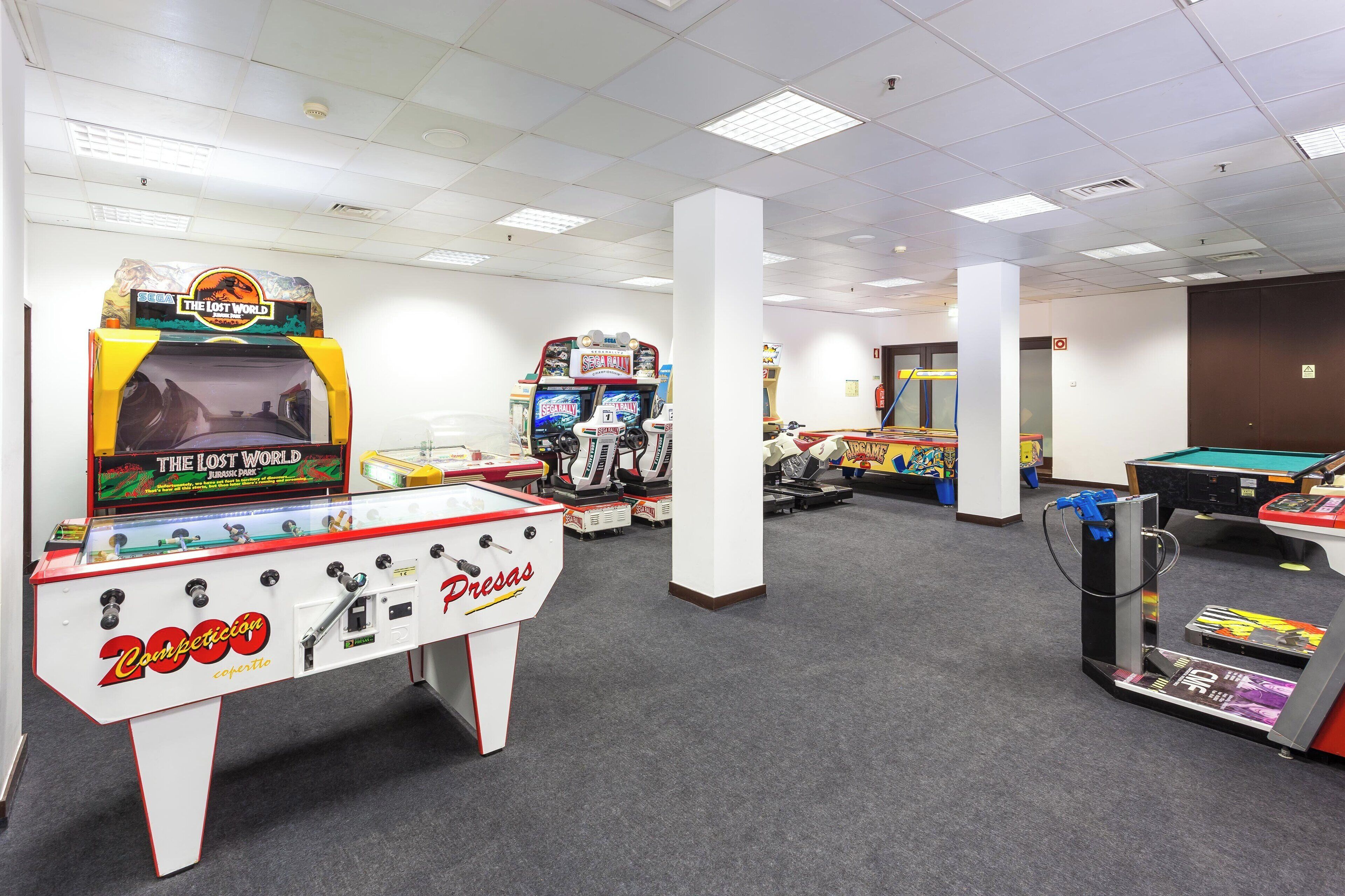 Une salle avec des jeux d’arcade, notamment les jeux « The Lost World » et « Dresas », une table de billard et un jeu de fléchettes.