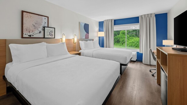A hotel room with two beds, a desk, a TV, and a window with curtains. - Spark by Hilton Brunswick (Brunswick)