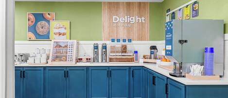 Una cocina con armarios azules, un refrigerador y una pared con un cartel que dice 'Delight in the day'.