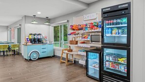 A modern kitchenette with a blue cart, a refrigerator, and a microwave. - Spark by Hilton Brunswick (Brunswick)