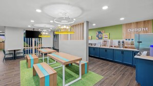A modern café with wooden tables, green artificial grass, and a blue counter with a coffee machine. - Spark by Hilton Brunswick (Brunswick)