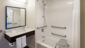 A modern bathroom with a white sink, mirror, and bathtub.