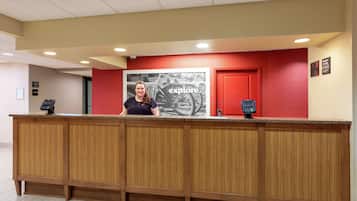 A reception desk with a wooden finish, a red wall, and a large 'explore' poster.
