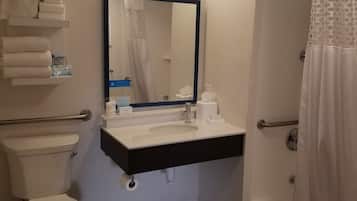 A bathroom with a toilet, sink, mirror, shower, and towel rack.