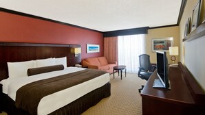 Une chambre d’hôtel avec un grand lit, un bureau avec un ordinateur, une chaise et un canapé.