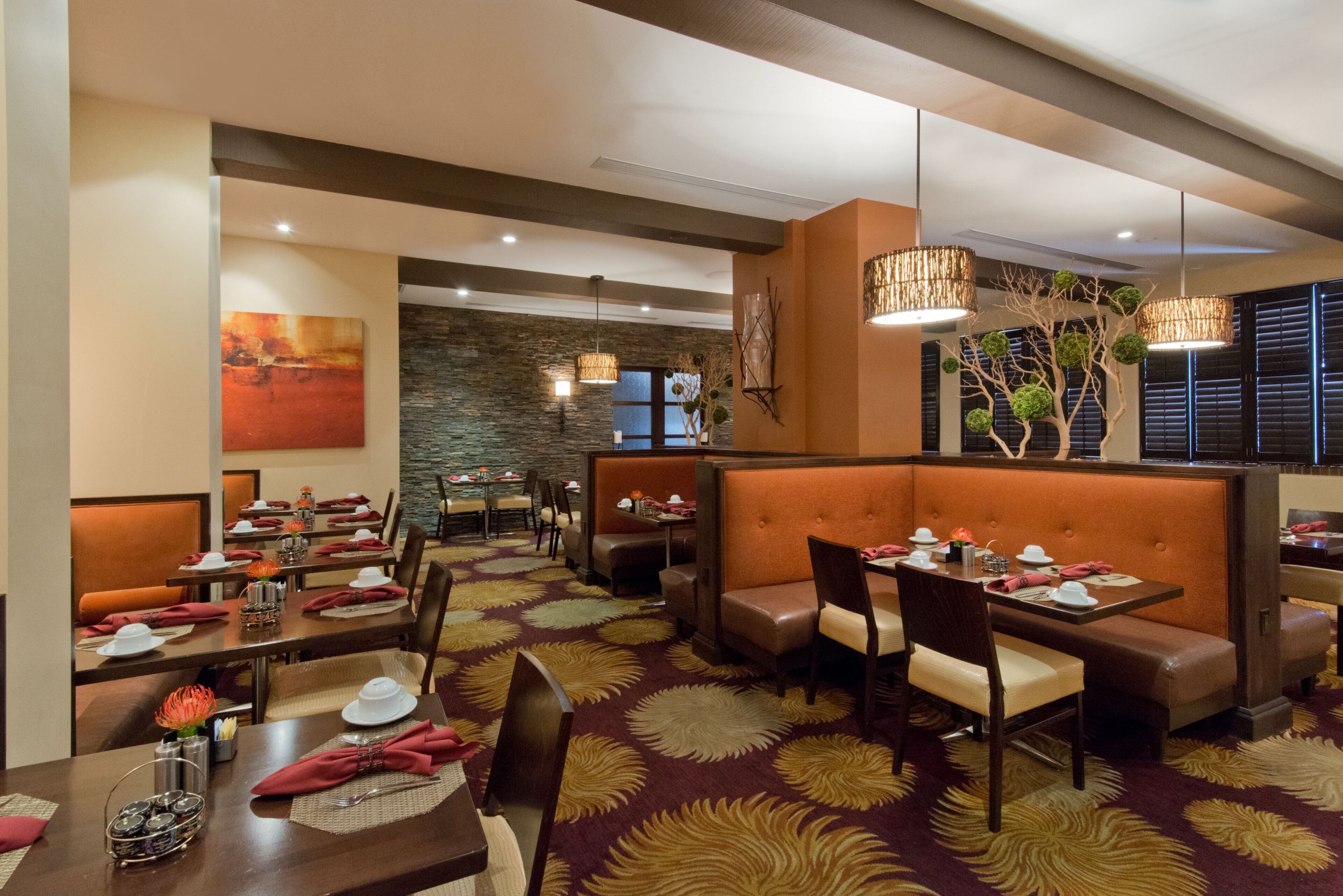 A restaurant with booths, tables, and a patterned carpet.