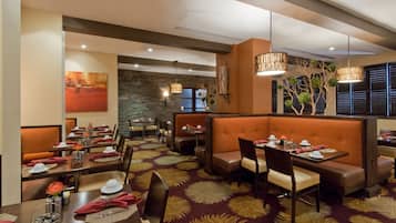 A restaurant with booths, tables, and a patterned carpet.