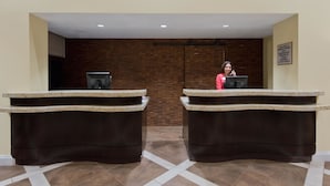 Un espace d’accueil d’hôtel comprenant deux comptoirs de réception, un réceptionniste et un panneau indiquant que l’hôtel est une propriété privée.