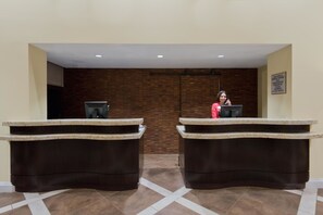A hotel reception area with two reception desks, a receptionist, and a sign indicating the hotel is privately owned. - Crowne Plaza Albuquerque by IHG (Albuquerque)