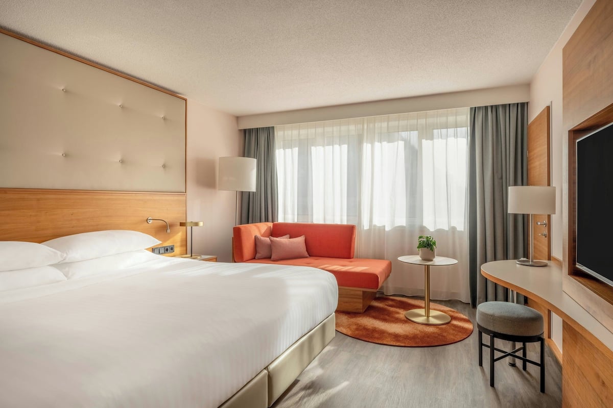 Hotellihuone, jossa on suuri sänky, sohva, työpöytä ja televisio.