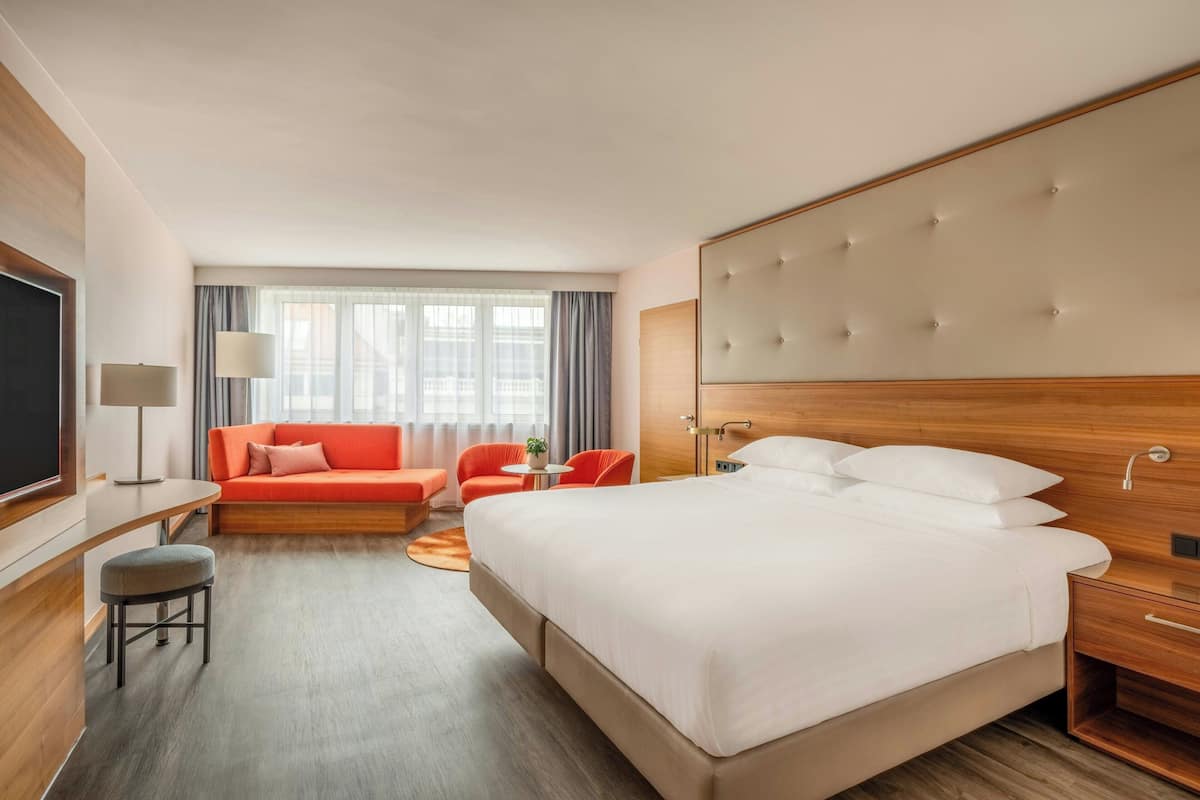 Hotellihuone, jossa on suuri sänky, sohva, työpöytä ja televisio.
