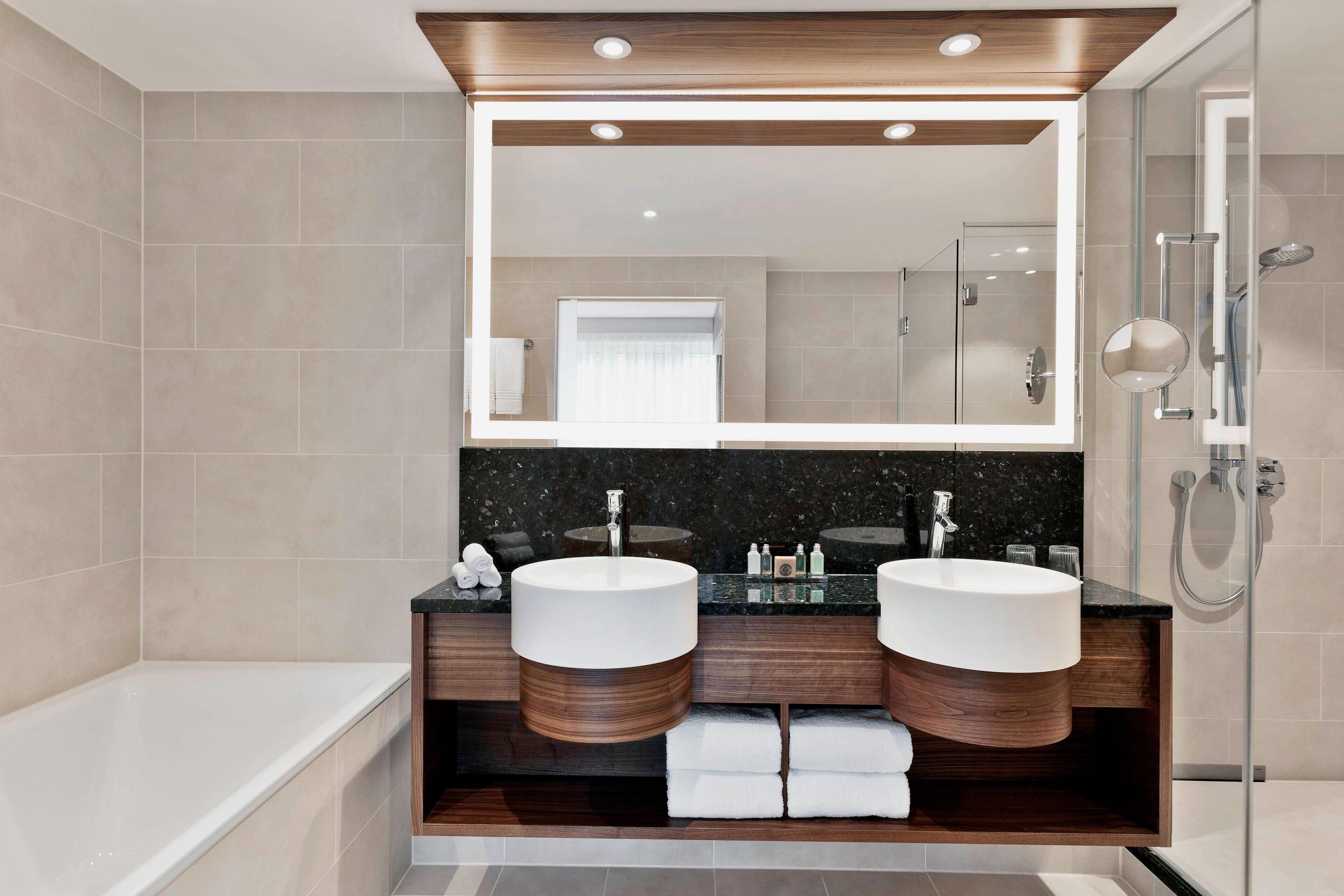 Un bagno moderno con due lavandini, uno specchio grande e una doccia a filo pavimento.