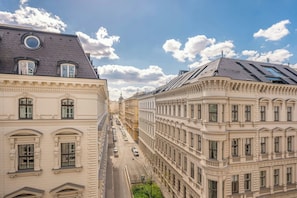 A street view of a city with historic buildings, a clear sky, and a few cars on the road.