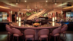 A modern bar area with a central island, bar stools, and a staircase leading to an upper level. - Vienna Marriott Hotel (Vienna)