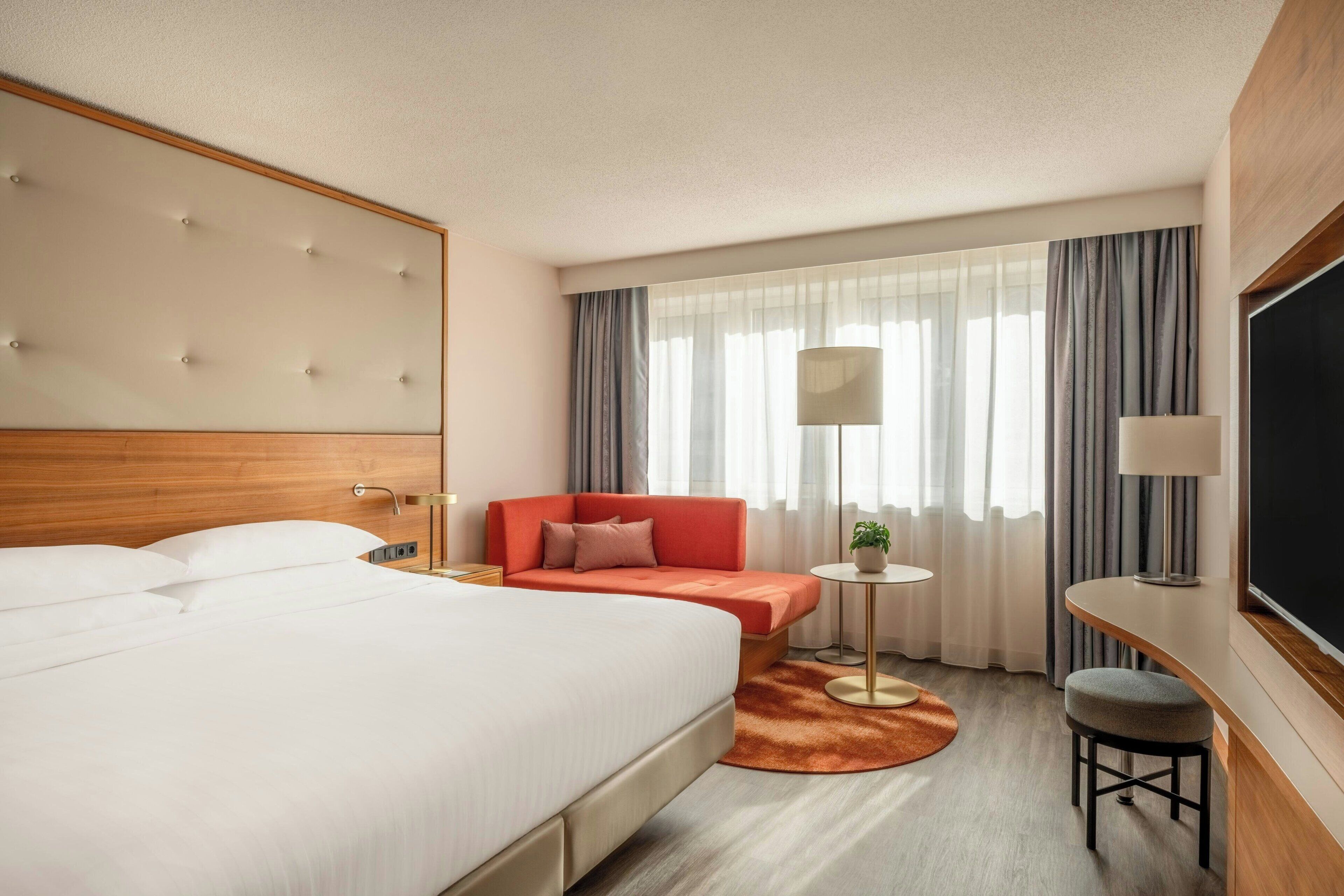 Una habitación de hotel con una cama grande, un sofá, una mesita y un televisor.