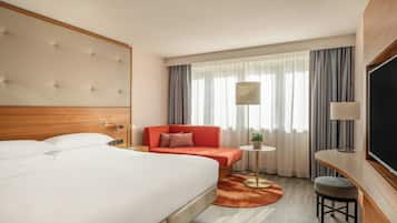 Una habitación de hotel con una cama grande, un sofá, una mesita y un televisor.