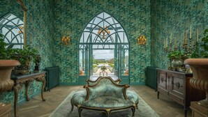 A room with a large arched window, a chandelier, and a vintage sofa. - Glenlo Abbey Hotel (Galway)