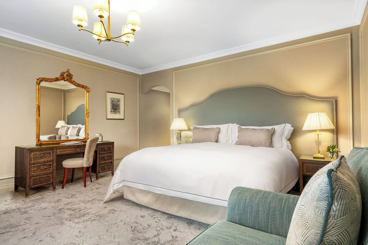 Ein Hotelzimmer mit einem großen Bett, einem Frisiertisch mit Spiegel, einem Schreibtisch und einem Stuhl.