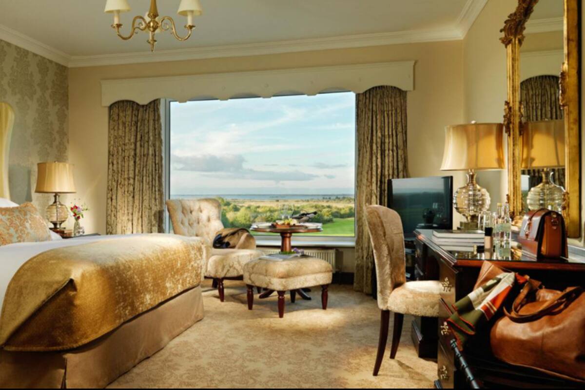Ein Hotelzimmer mit einem großen Bett, einem Schreibtisch, einem Stuhl und Blick auf die Landschaft.