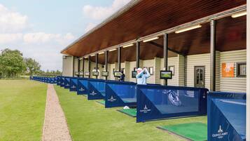 Un campo de prácticas de golf con múltiples calles y una zona de estar cubierta.