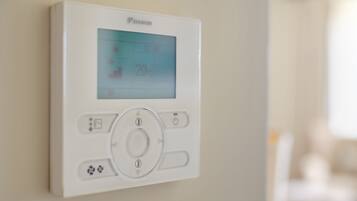 A wall-mounted thermostat with a digital display, control buttons, and a brand name.