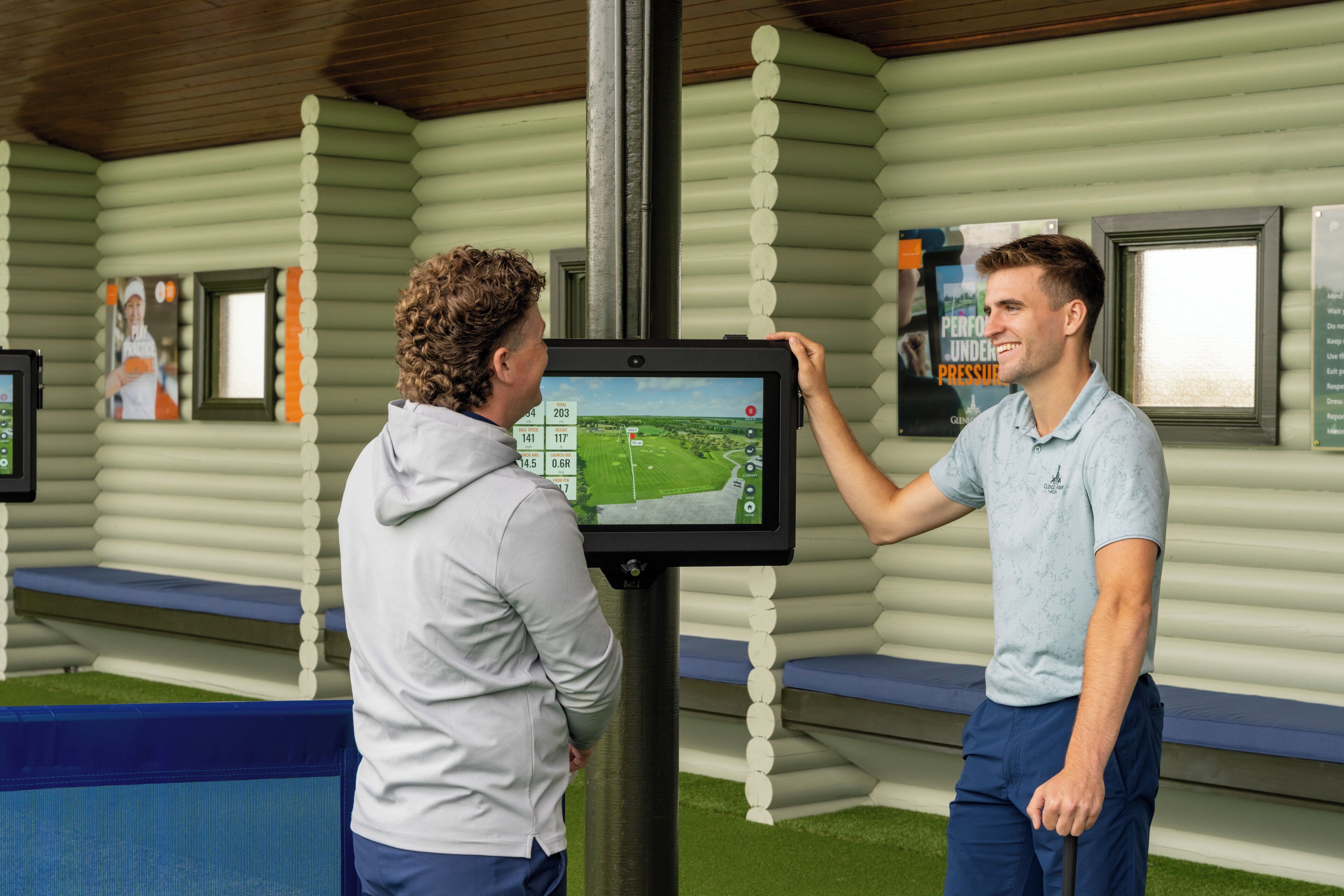 A man interacting with a digital kiosk in a log cabin-style building.