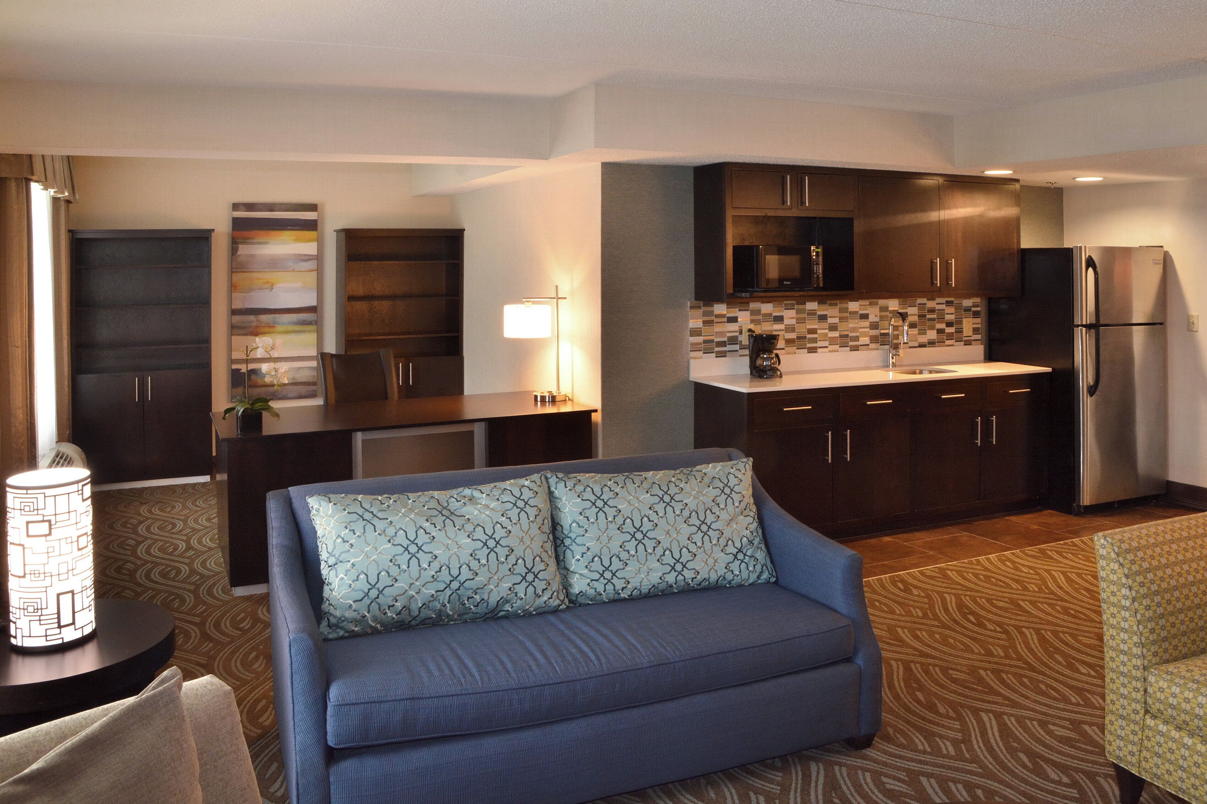A compact living space with a kitchenette, a sofa, and a patterned rug.