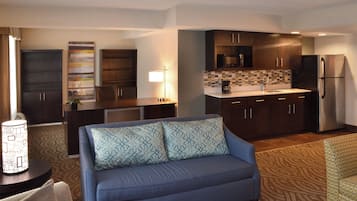 A compact living space with a kitchenette, a sofa, and a patterned rug.