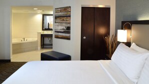A hotel room with a large bed, a bathroom with a bathtub, a desk, and a nightstand. - Holiday Inn Youngstown South by IHG (Boardman)