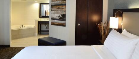 A hotel room with a large bed, a bathroom with a bathtub, a desk, and a nightstand.