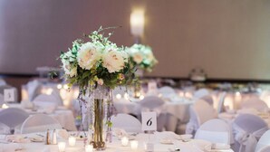 A banquet table with a floral centerpiece, candles, and a table number sign. - Holiday Inn Youngstown South by IHG (Boardman)