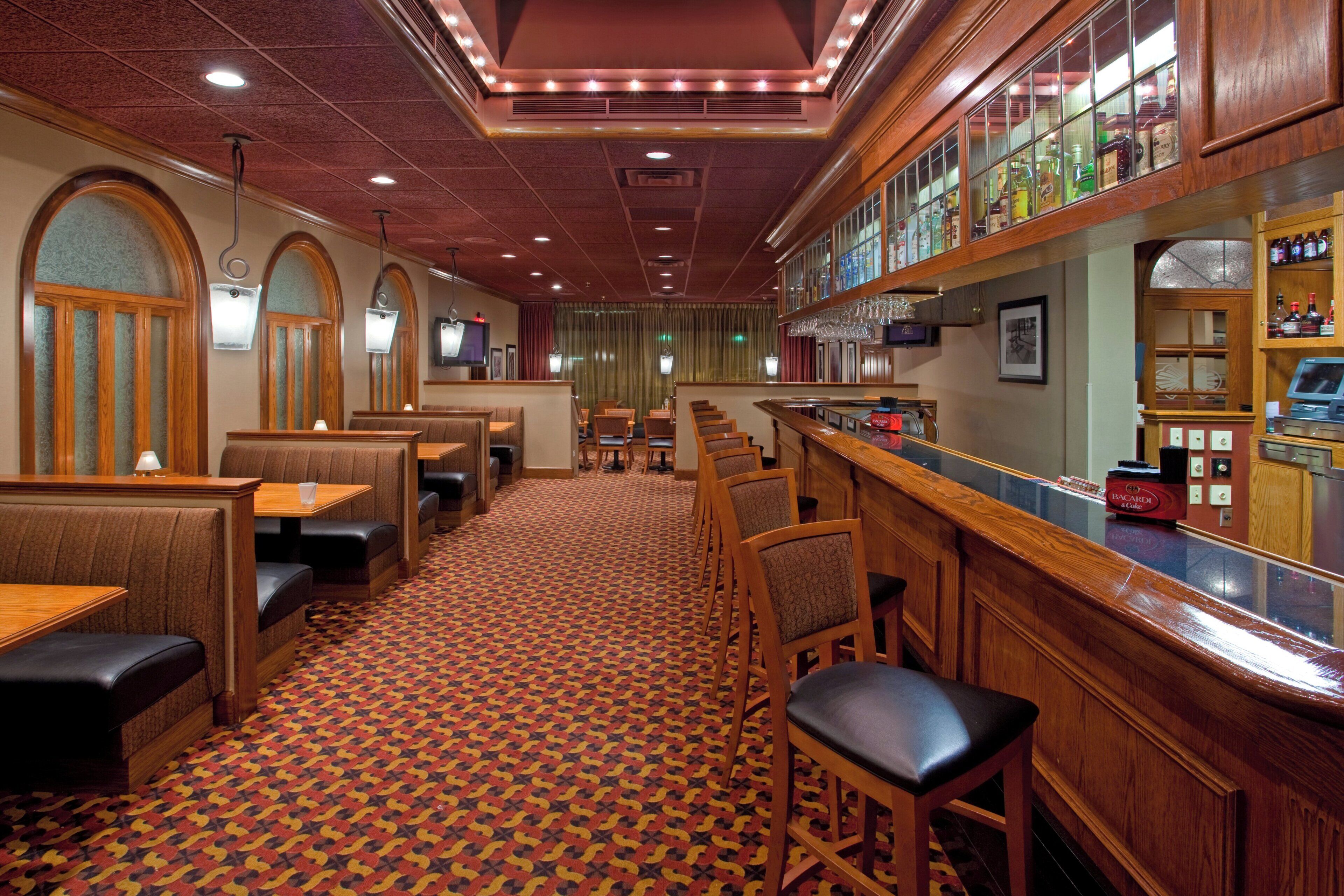 A restaurant interior with booths, a bar area, and a patterned carpet.