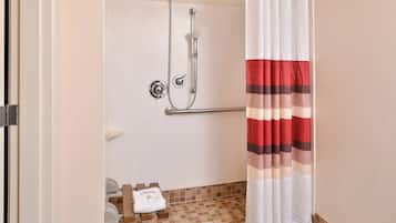 A shower with a handheld showerhead, a grab bar, and a towel rack with a folded towel.